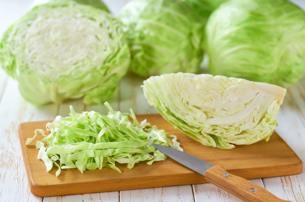 Whole-and-sliced-fresh-green-cabbage-on-a-white-wooden-table