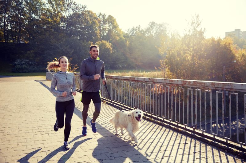 couple running with dog outdoors