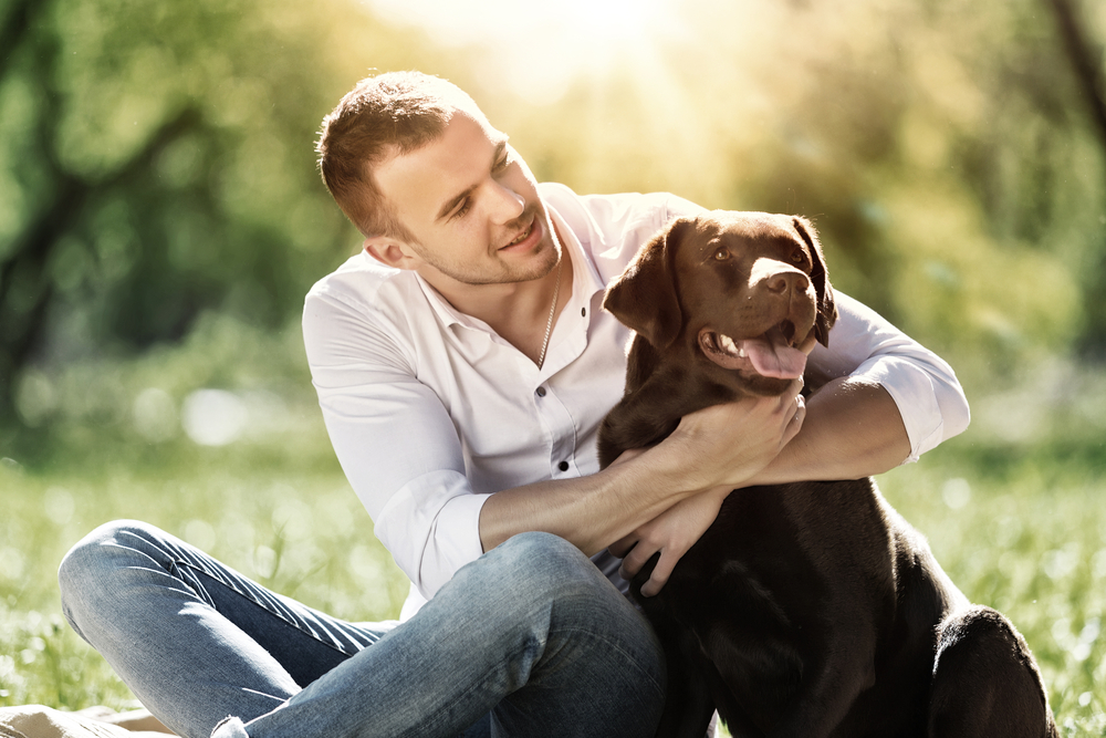 male owner hugging his dog at the park