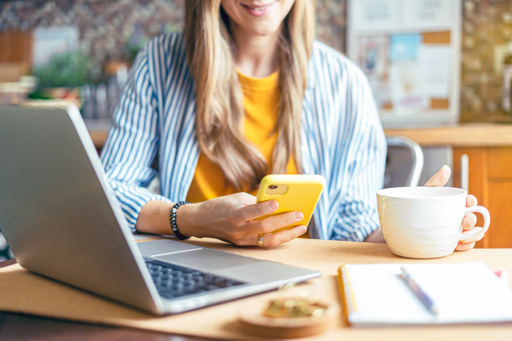 Woman on her phone in front of a computer