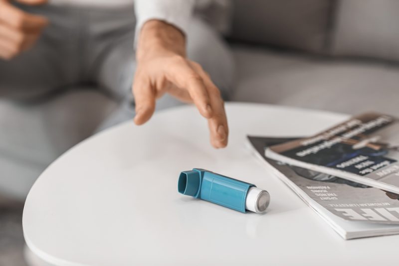 Man taking inhaler from table