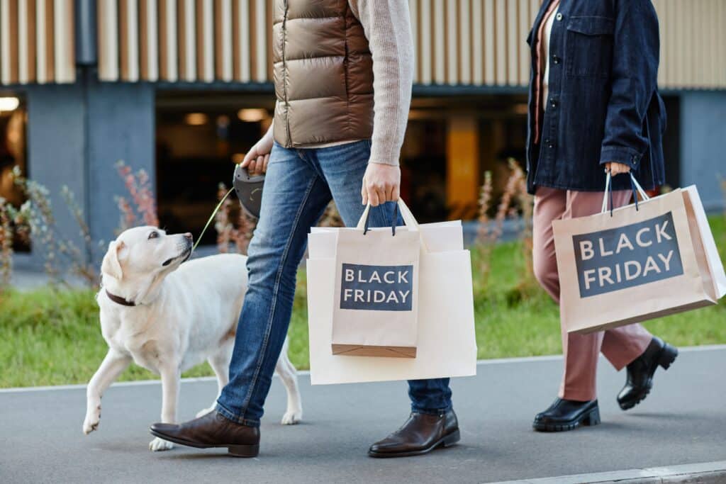 adult couple holding shopping bags with Black Friday while walking outdoors