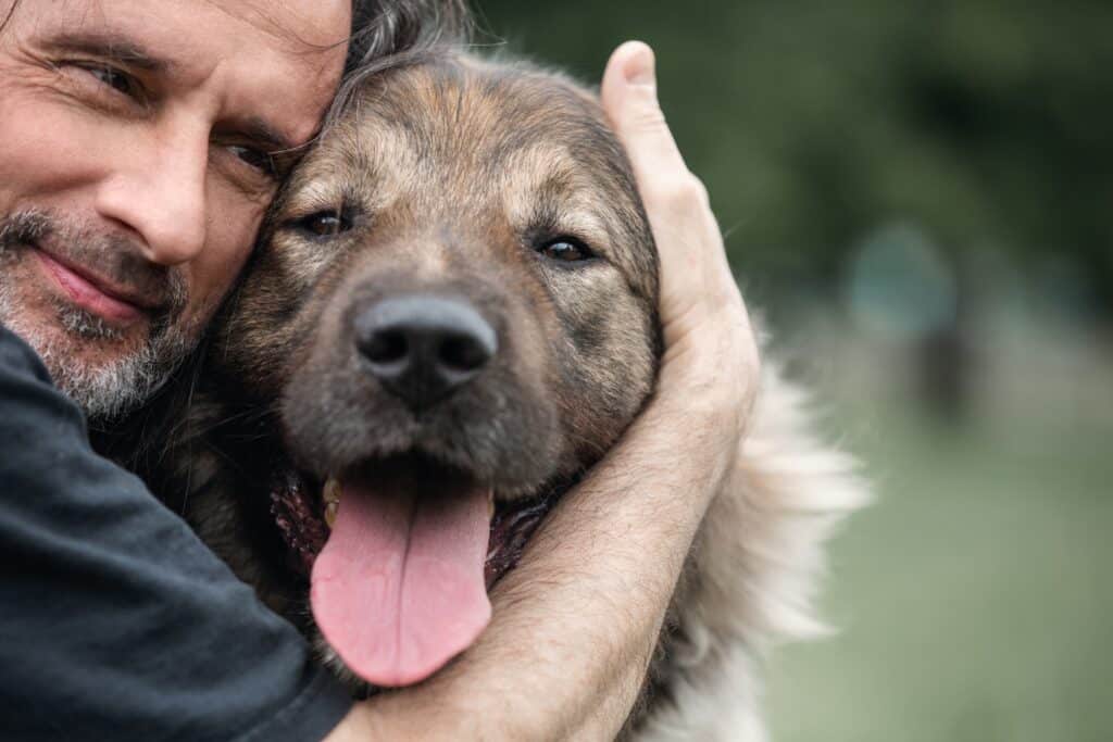 A middle aged man hugs a dog on a walk 1024x683 1