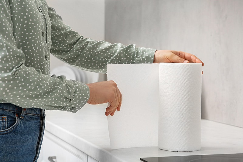 woman tearing paper towels in kitchen New Africa Shutterstock